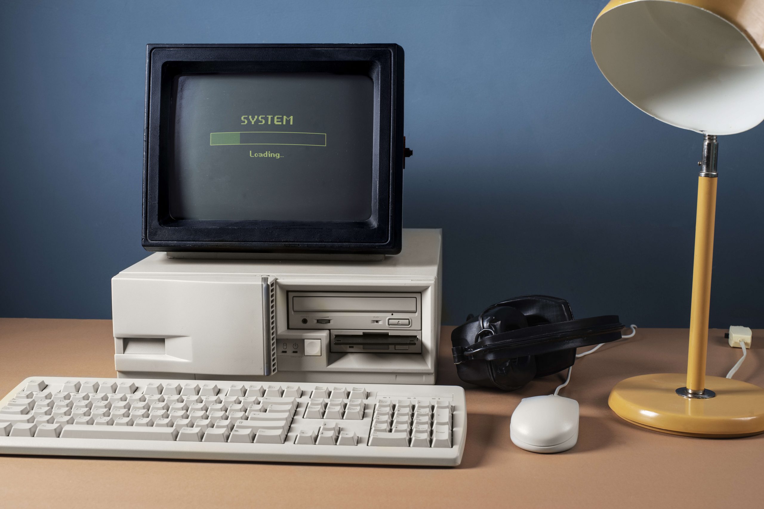 An old computer with a bulky monitor displaying a loading screen, representing the challenges of migrating legacy systems to the cloud.
